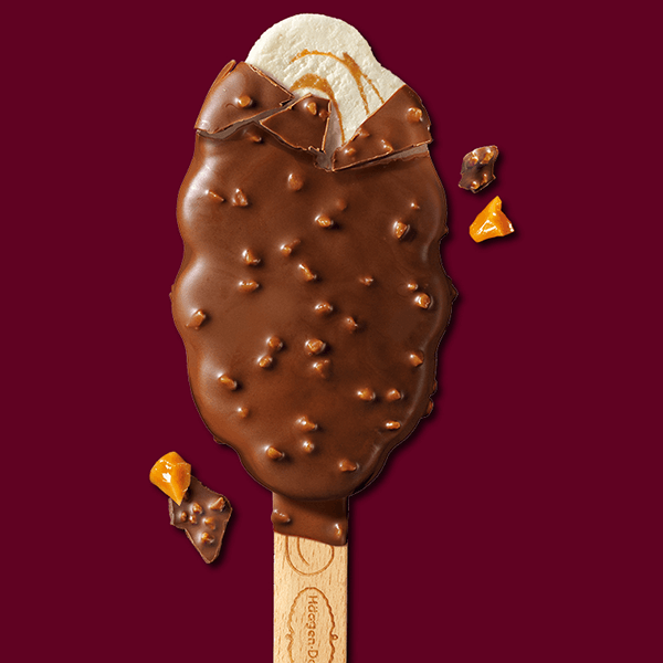 haagen dazs ice cream bar with chocolate coating & crunchy nut pieces, partially bitten to reveal creamy vanilla ice cream inside